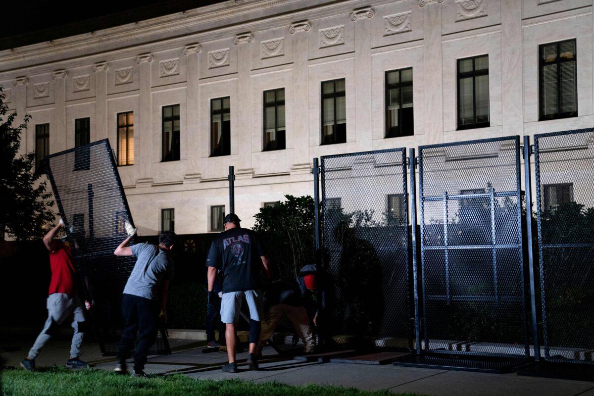 Workers set up fencing around the Supreme Court in Washington late on May 4, 2022. (Stefani Reynolds/AFP via Getty Images)