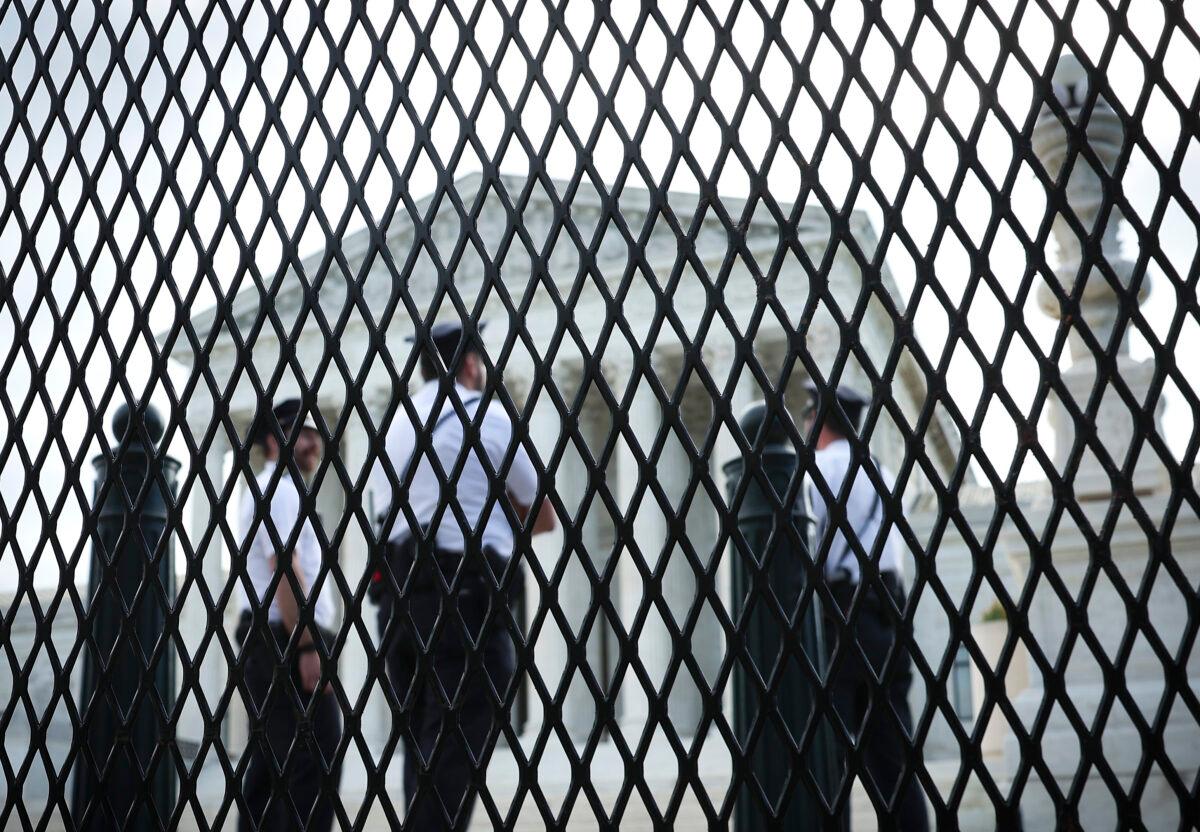 Law enforcement officers talk as they stand behind fencing that was erected around the Supreme Court building in Washington on May 5, 2022. (Win McNamee/Getty Images)