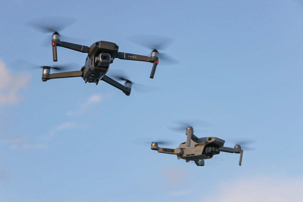 A DJI Mavic 2 Pro and DJi Mavic Mini made by the Chinese drone maker fly near each other in Miami, Fla, on Dec. 15, 2021. (Joe Raedle/Getty Images)