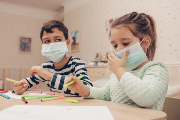 Undated image of two children wearing masks playing with colouring pens. (L Julia/Shutterstock)