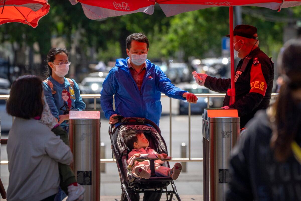 A security guard wearing a face mask takes the temperature of visitors as they enter a public park in Beijing on April 30, 2022, the first day of the Labor Day holiday period in China. (Mark Schiefelbein/AP Photo)