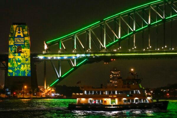 A Sydney ferry sails past the illuminated pylon of the Sydney Harbour Bridge ahead of the final vote for the hosting of the Rugby World Cups, on May 12, 2022. (Mark Baker/AP Photo)