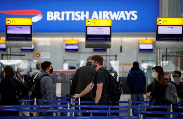 Passengers stand in a line for the British Airways check-in desks in the departures area of Terminal 5 at Heathrow Airport in London on May 17, 2021. (John Sibley/Reuters)