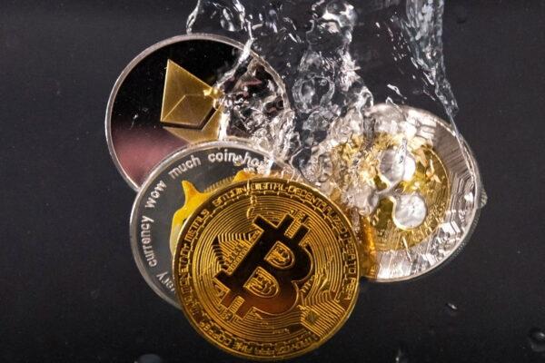 Souvenir tokens representing cryptocurrency networks Bitcoin, Ethereum, Dogecoin, and Ripple plunge into water in this illustration on May 17, 2022. (Dado Ruvic/Illustration/Reuters)
