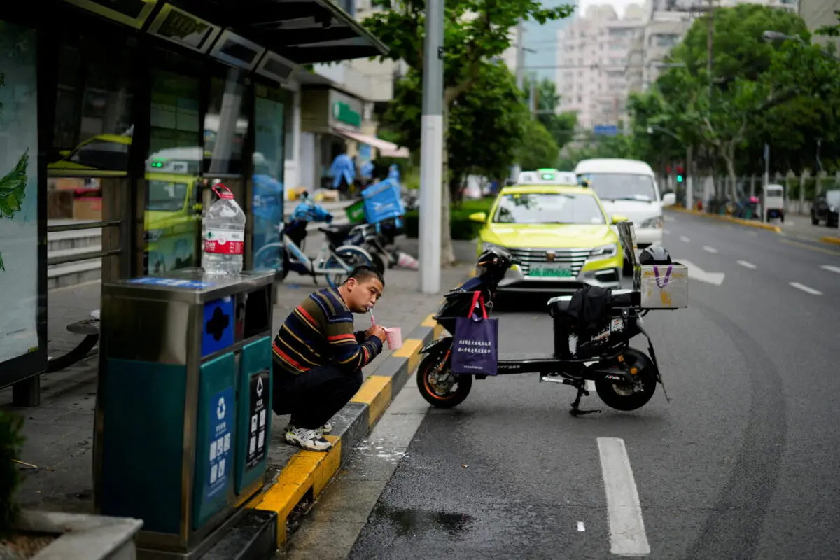 A delivery worker brushes his teeth on a street in Shanghai on May 12, 2022. (Aly Song/Reuters)