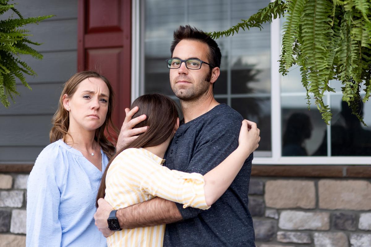 Erin Lee and her husband, Jonathan, pose for a portrait with their 13-year-old daughter, who wished to remain anonymous, at their home in Wellington, Colo., on May 7, 2022. (Michael Ciaglo for The Epoch Times)