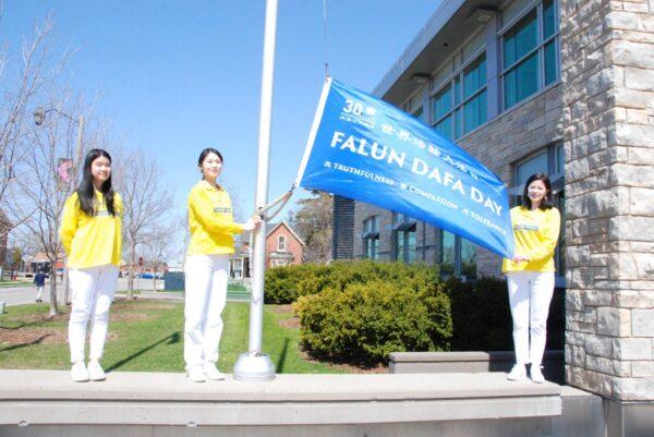 Falun Dafa adherents raise a flag in celebration of the 30th anniversary of the spread of the spiritual practice, in the City of Milton, Ont., on May 2022. (Arek Rusek/The Epoch Times)
