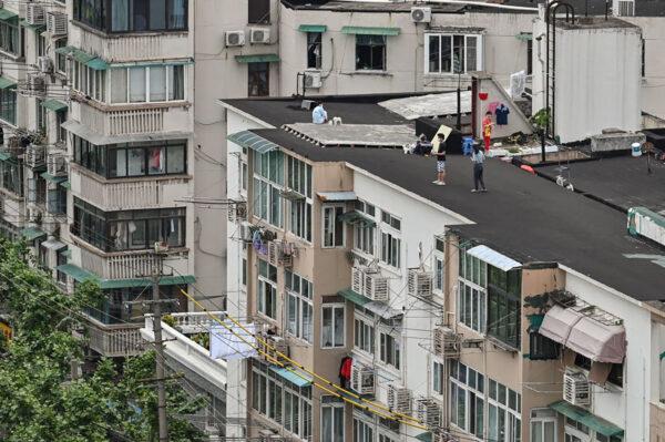 People stand on a rooftop of a building during a COVID-19 lockdown in the Jing'an District in Shanghai on May 7, 2022. (Hector Retamal/AFP via Getty Images)