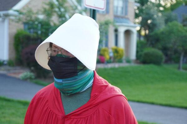 A pro-abortion "performative artist" dressed as a "handmaid" while walking near Justice Amy Coney Barrett's house in Falls Church, Virginia on May 11, 2022 (Jackson Elliott/The Epoch Times)