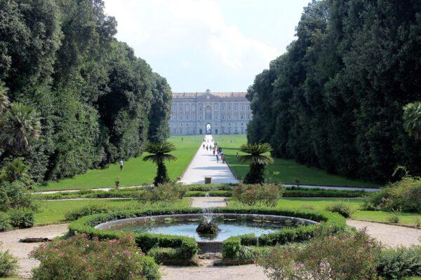 This frontal view of Reggia di Caserta elegantly hints at the grandeur that lies in store for visitors to the Royal Palace. Surrounded by greenery, the palace is equally famous for its massive grounds which cover 300 acres. (Miguel Hermoso Cuesta/<a class="mw-mmv-license" href="https://creativecommons.org/licenses/by-sa/3.0" target="_blank" rel="noopener">CC BY-SA 3.0</a>)