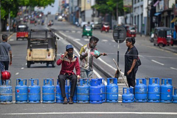 Consumers in long lines to buy cooking gas use their empty cylinders to block a main intersectional road in Colombo on May 8, 2022, after a local store ran out of supplies. (Ishara S. Kodikara/AFP via Getty Images)