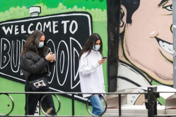 Two girls walk past a "Welcome to Burwood" mural in Sydney, Australia, on July 24, 2021. (Jenny Evans/Getty Images)