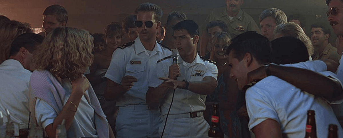 (Center): Goose (Anthony Edwards, L), and Maverick (Tom Cruise) team-serenade their (unbeknownst to them) flight instructor (Kelly McGillis, L) in "Top Gun: Maverick." (Paramount Pictures)