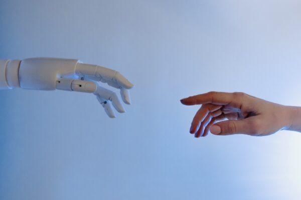 Stock photo of a person reaching out for a robot. (Tara Winstead/Pexels)