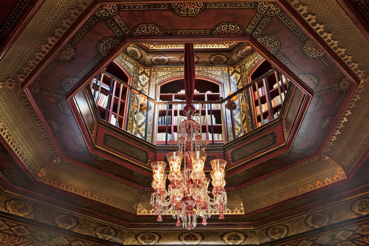 A dramatic ceiling for an octagonal library has layers that both hide the lighting and air conditioning and provide myriad surfaces to decorate with hand-printed and -painted papers, brass, and gilt work. (Courtesy of Alidad)