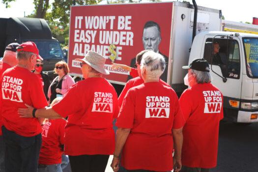 A vehicle displaying political advertising makes it's way past Labor Party supporters at a pre-polling booth in the suburb of Wanneroo in Perth, Australia on May 16, 2022. (Lisa Maree Williams/Getty Images)