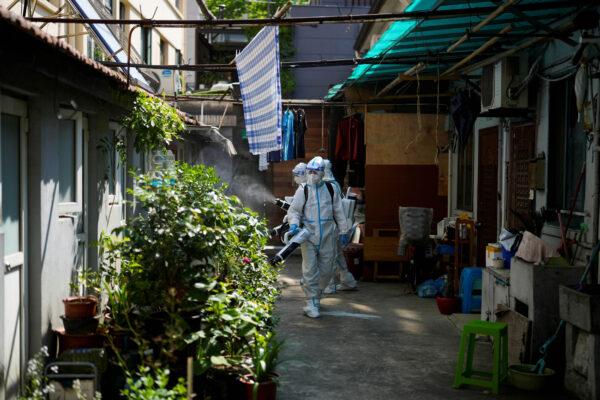 Workers in protective suits disinfect a closed residential area during lockdown in Shanghai, on May 18, 2022. (Aly Song/Reuters)