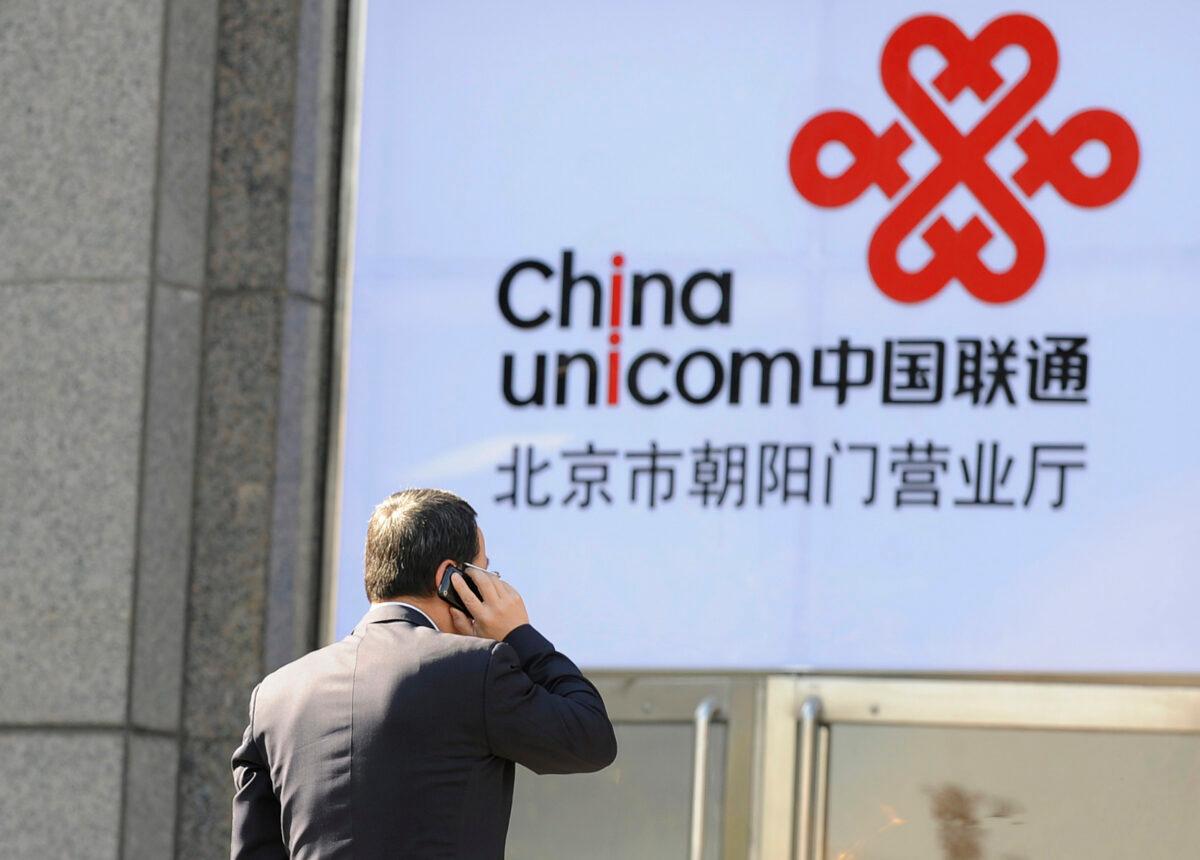 An office worker talks on a mobile phone in front of a China Unicom logo, California-based Apple's partner in China, in Beijing on January 5, 2012. (Liu Jin/AFP via Getty Images)