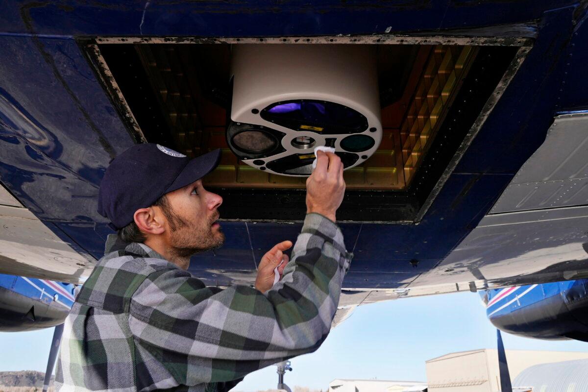 Dan Berisford, an engineer with Airborne Snow Observatories, cleans a laser mapping device used to measure snow that is mounted under an airplane, in Gunnison, Colo., on April 18, 2022. (Brittany Peterson/AP Photo)