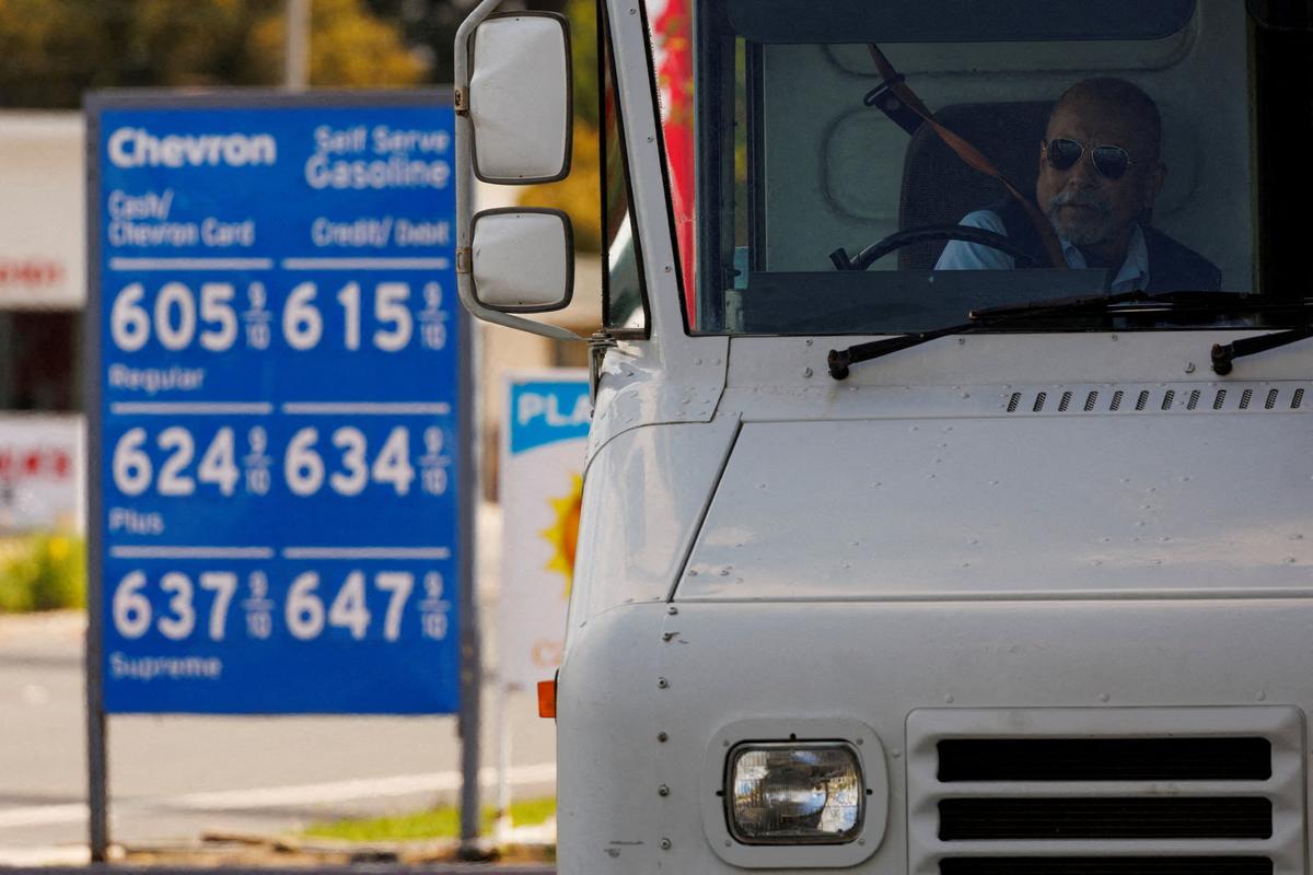 A U.S. postal worker puts his seatbelt on after filling up his vehicle at a gas station in Garden Grove, Calif., on March 29, 2022. (Mike Blake/Reuters)