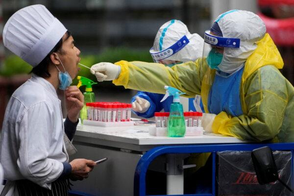 A medical worker in a protective suit collects a swab sample from a chef for nucleic acid testing, during a lockdown, amid the coronavirus disease (COVID-19) pandemic, in Shanghai, China, May 13, 2022. (Aly Song/Reuters)