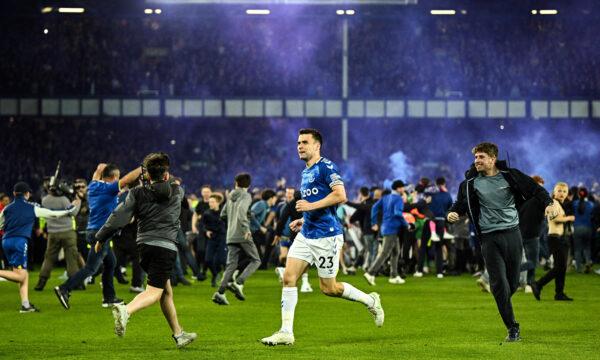 Everton player Seamus Coleman runs past fans invading the pitch to celebrate Everton escaping relegation at Goodison Park in Liverpool, England, on May 19, 2022. (Oli Scarff/AFP via Getty Images)