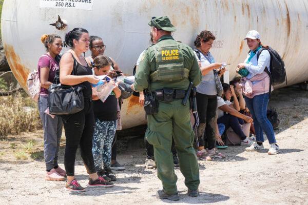 A Border Patrol agent detains and organizes a large group of illegal immigrants near Eagle Pass, Texas, on May 20, 2022. (Charlotte Cuthbertson/The Epoch Times)