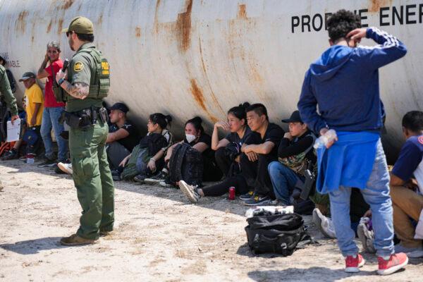  A Border Patrol agent detains and organizes a large group of illegal immigrants near Eagle Pass, Texas, on May 20, 2022. (Charlotte Cuthbertson/The Epoch Times)