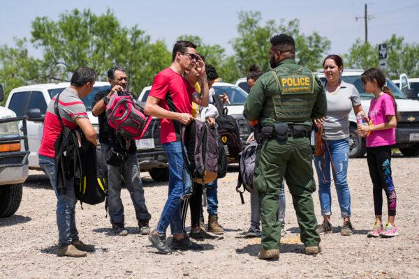 A Border Patrol agent organizes a group of illegal immigrants near Eagle Pass, Texas, on May 20, 2022. (Charlotte Cuthbertson/The Epoch Times)
