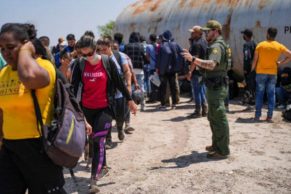 A Border Patrol agent organizes a large group of illegal immigrants near Eagle Pass, Texas, on May 20, 2022. (Charlotte Cuthbertson/The Epoch Times)