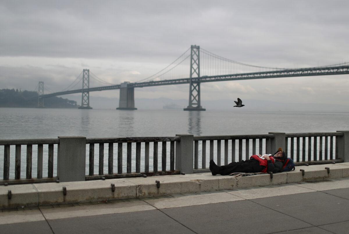 A homeless man sleeps on the sidewalk near the San Francisco–Oakland Bay Bridge in San Francisco on Dec. 5, 2019. (Justin Sullivan/Getty Images)