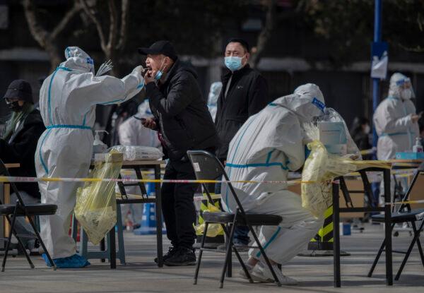 Health-care workers in protective clothing conduct large-scale screening of local residents for nucleic acid after a new Omicron surge in Beijing in April 2022. (Kevin Frayer/Getty Images)