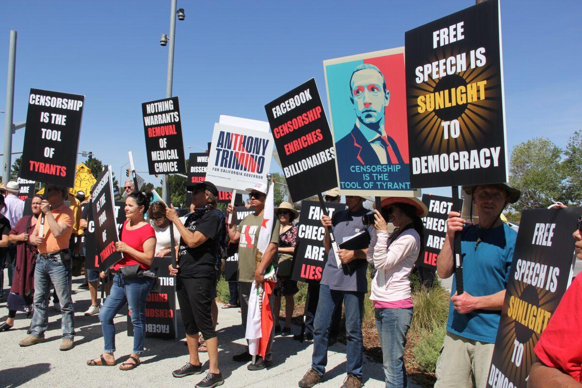 Protesters hold signs denouncing Facebook and CEO Mark Zuckerberg at the Humanity Against Censorship rally in front of Meta headquarters in Menlo Park, Calif., on May 19, 2022. (The Epoch Times)