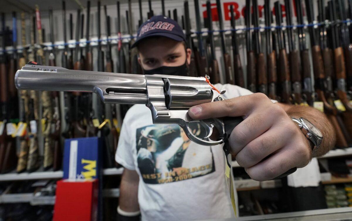 A salesman shows off weapons for sale at Coliseum Gun Traders Ltd. in Uniondale, N.Y. on Sept. 25, 2020. (Timothy A. Clary/AFP via Getty Images)