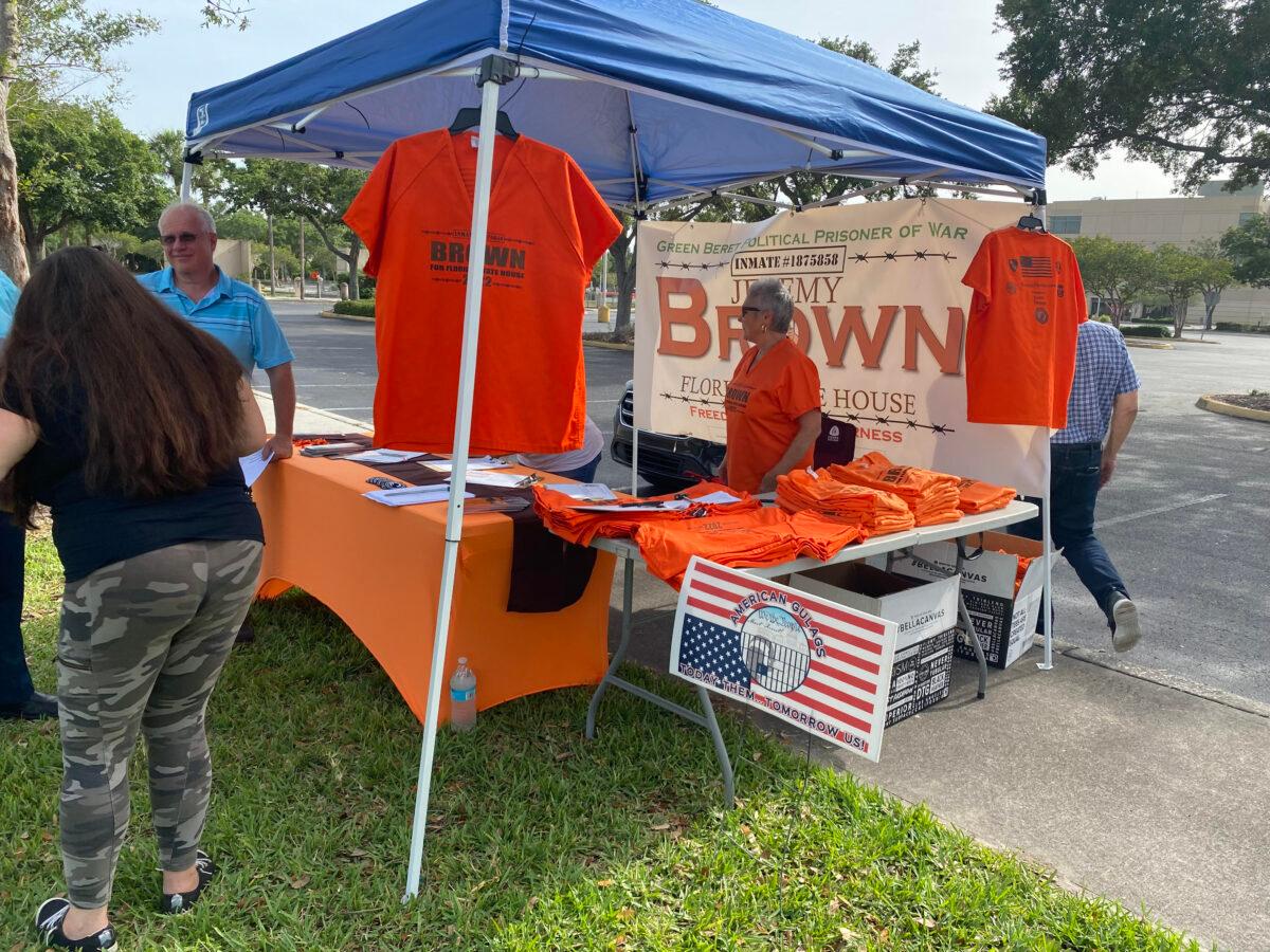 Sirena Pellarolo sells orange T-shirts in the campaign tent at a rally held outside of the Pinellas County Jail in Clearwater, Fla., in support of Jeremy Brown, a Jan. 6 prisoner and candidate for Florida State Representative, on May 22, 2022. (Patricia Tolson/The Epoch Times)