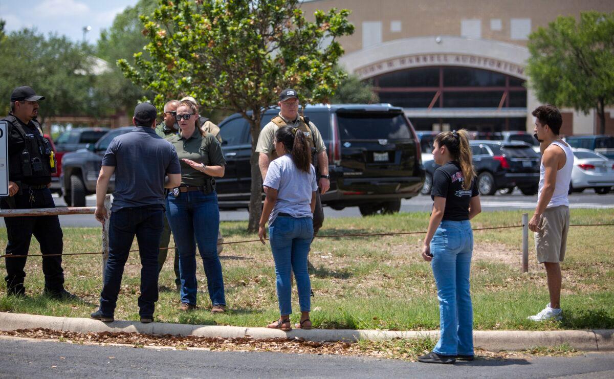 A law enforcement officer speaks with people outside Uvalde High School after a shooting took place at nearby Robb Elementary School, in Uvalde, Texas, on May 24, 2022. (William Luther/The San Antonio Express-News via AP)