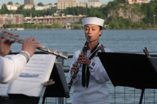 A clarinetist, part of a small U.S. Navy band, plays on Pier 76, in Manhattan, as the fleet entered New York's Hudson River on May 25, 2022. (Richard Moore/The Epoch Times)