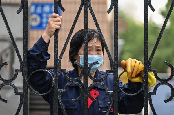A worker looks past a fence in a compound during a COVID-19 lockdown in the Jing'an district of Shanghai on May 25, 2022. (Hector Retamal/AFP via Getty Images)