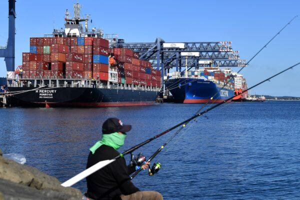 Container ships are seen as a man fishes at the Port Botany in Sydney, Australia, on May 3, 2022. (Saeed Khan/AFP via Getty Images)