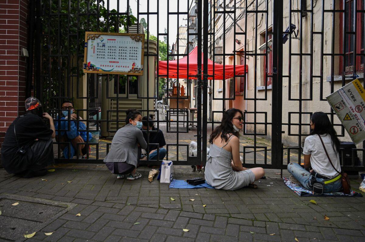 People with a two-three hour pass from their residential compounds speak with locked down residents during a COVID-19 lockdown in the Jing'an district of Shanghai on May 27, 2022. (Hector Retamal/AFP via Getty Images)