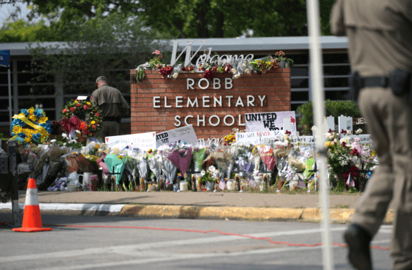 Texas state troopers place flowers brought by locals to the Robb Elementary School makeshift memorial on May 27, 2022. (Charlotte Cuthbertson/Epoch Times)