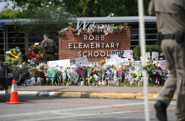 Texas state troopers place flowers brought by locals to the Robb Elementary School makeshift memorial on May 27, 2022. (Charlotte Cuthbertson/Epoch Times)