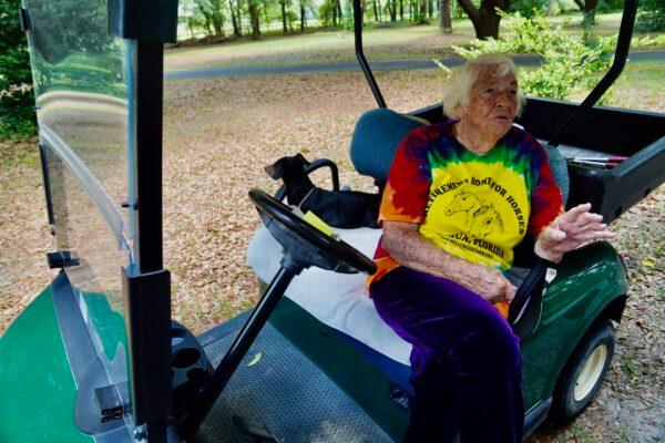 Founder Mary Gregory pauses on a golf cart jaunt around 335-acre Mill Creek Farm to chat with visitors about her love for the horses there, while one of her many rescue dogs patiently waits for the ride to resume. (Nanette Holt/The Epoch Times)