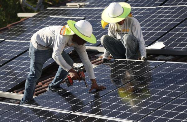 Roger Garbey (L) and Andres Hernandez, from the Goldin Solar company, install a solar panel system on the roof of a home a day after the Trump administration announced it will impose duties of as much as 30 percent on solar equipment made abroad, in Palmetto Bay, Fla., on Jan. 23, 2018. (Joe Raedle/Getty Images)
