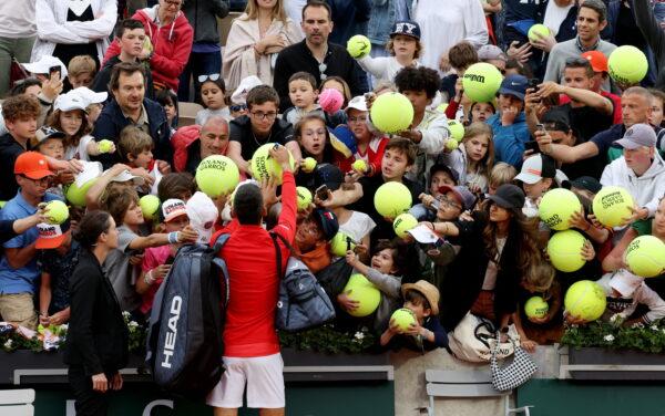 Serbia's Novak Djokovic signs autographs for fans after winning his second round match against Slovakia's Alex Molcan at the French Open in Roland Garros stadium in Paris on May 25, 2022. (Yves Herman/Reuters)