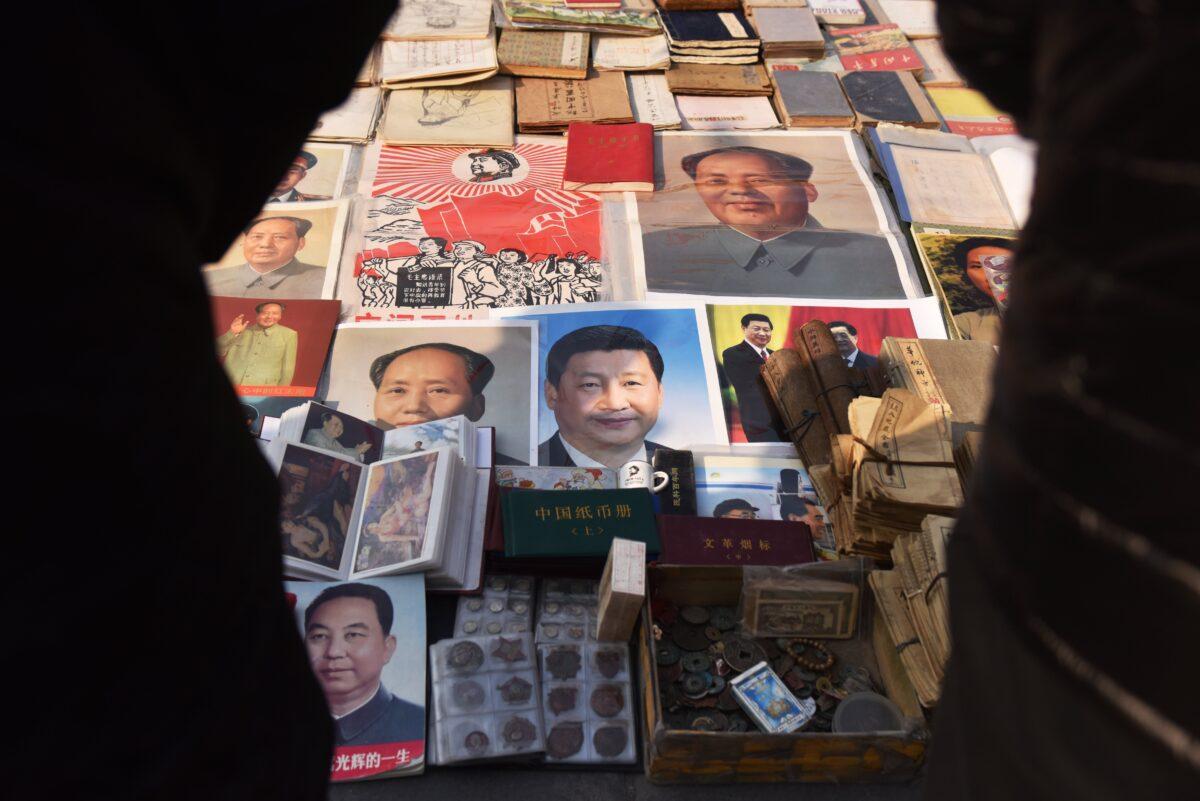 Customers look at posters of Chinese leader Xi Jinping (C), and late communist leader Mao Zedong (center L and top R), at a market in Beijing on Feb. 26, 2018. (Greg Baker/AFP via Getty Images)