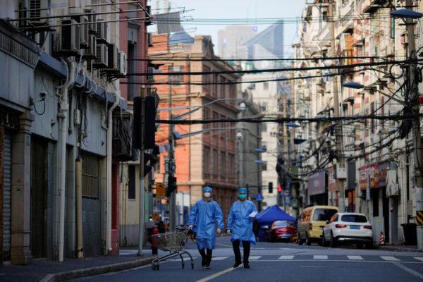 Workers in protective suits walk with a cart along a street during a lockdown on May 25, 2022. (Aly Song/Reuters)