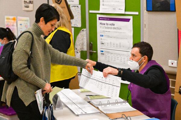 A polling officer hands over a ballot paper to a resident at the Australian general elections in Cook electorate of Sydney on May 21, 2022. (Saeed Khan/AFP via Getty Images)