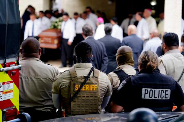 Law enforcement personnel look on as the caskets for Irma Garcia and husband Joe Garcia are carried by pallbearers following a joint service at Sacred Heart Catholic Church in Uvalde, Texas, on June 1, 2022. (Eric Gay/AP Photo)