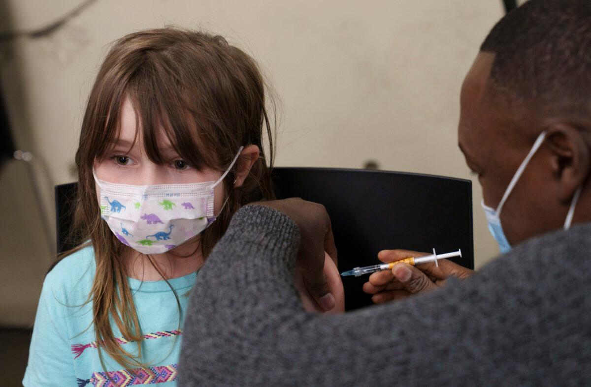 A young girl sits still as she receives a COVIC-19 vaccine during the second day of vaccination for children aged 5 to 11 in Montreal on Nov. 25, 2021. (The Canadian Press/Paul Chiasson)